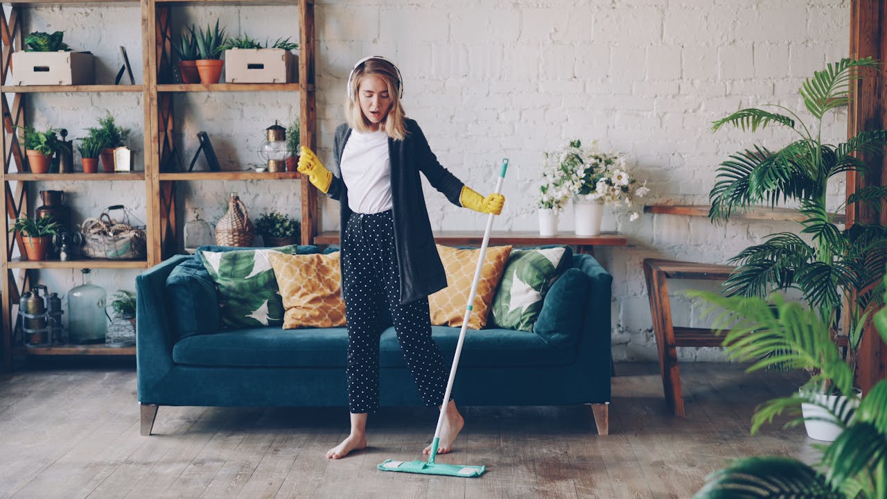 services-01 Woman cleaning living room with a mop at home, enjoying music.